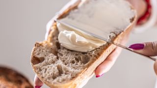 Butter being spread on a slice of sourdough bread