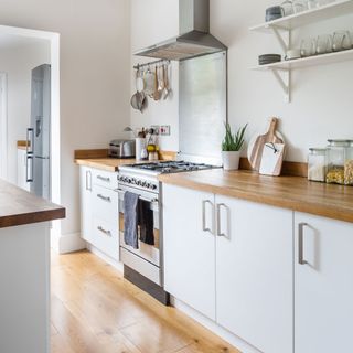 white kitchen with wooden counter and wooden floors