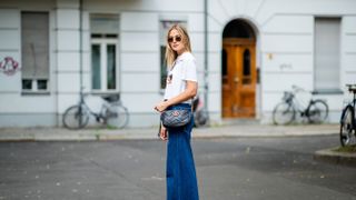 berlin, germany june 06 alessa winter wearing wide leg zara denim jeans, black gucci bag, white nubik sneakers, fiorucci tshirt with print, ray ban sunglasses on june 6, 2018 in berlin, germany photo by christian vieriggetty images