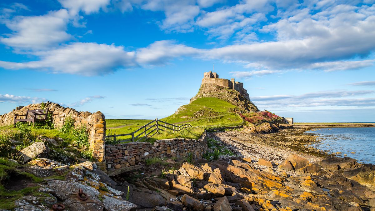 Lindisfarne castle seen from the rugged coast below it. 