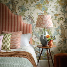 A patterned bedroom with double bed and headboard and patterned lampshade beside it