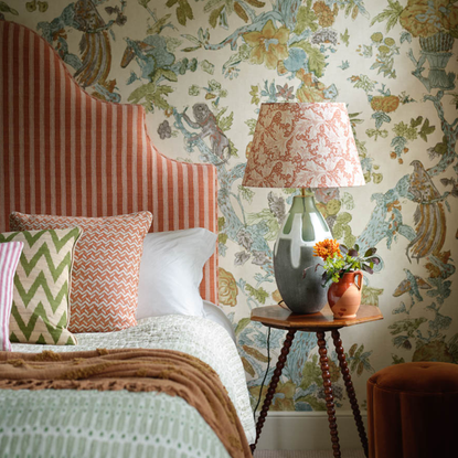 A patterned bedroom with double bed and headboard and patterned lampshade beside it