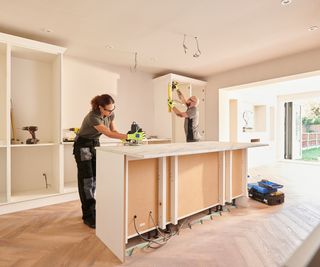 male and female kitchen fitters installing kitchen units