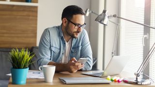 En person, der bruger en bærbar computer og en smartphone sammen.