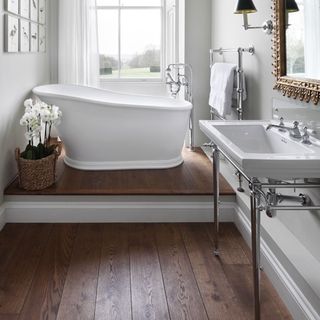 Wooden effect flooring in bathroom with freestanding white bath