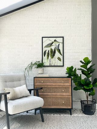 Abstract canvas print on the wall in hallway above wooden dresser with houseplants surrounding