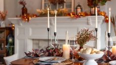 A table laid for Thanksgiving, with plates, wine glasses, flatware, and festive decor.