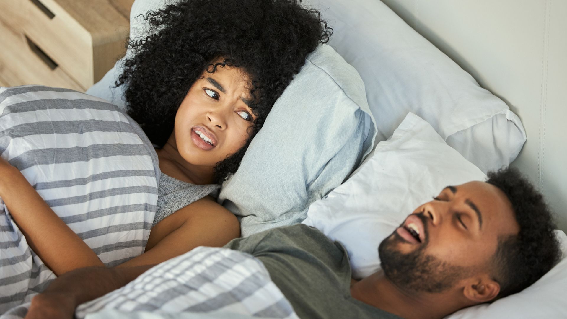 A woman getting annoyed with her partner's snoring in bed