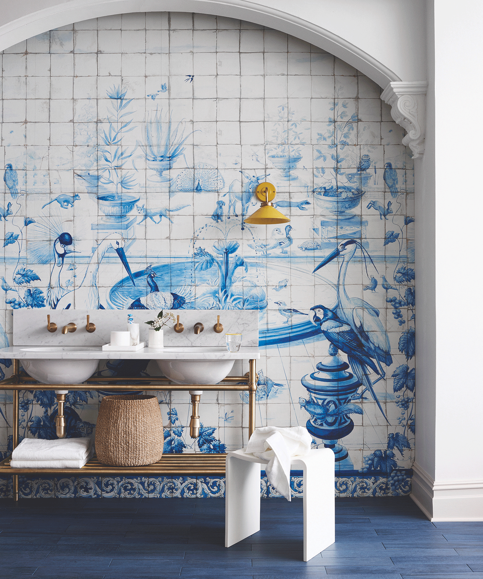Blue and white statement tile-effect wallpaper behind a double vanity unit with white sinks and gold taps