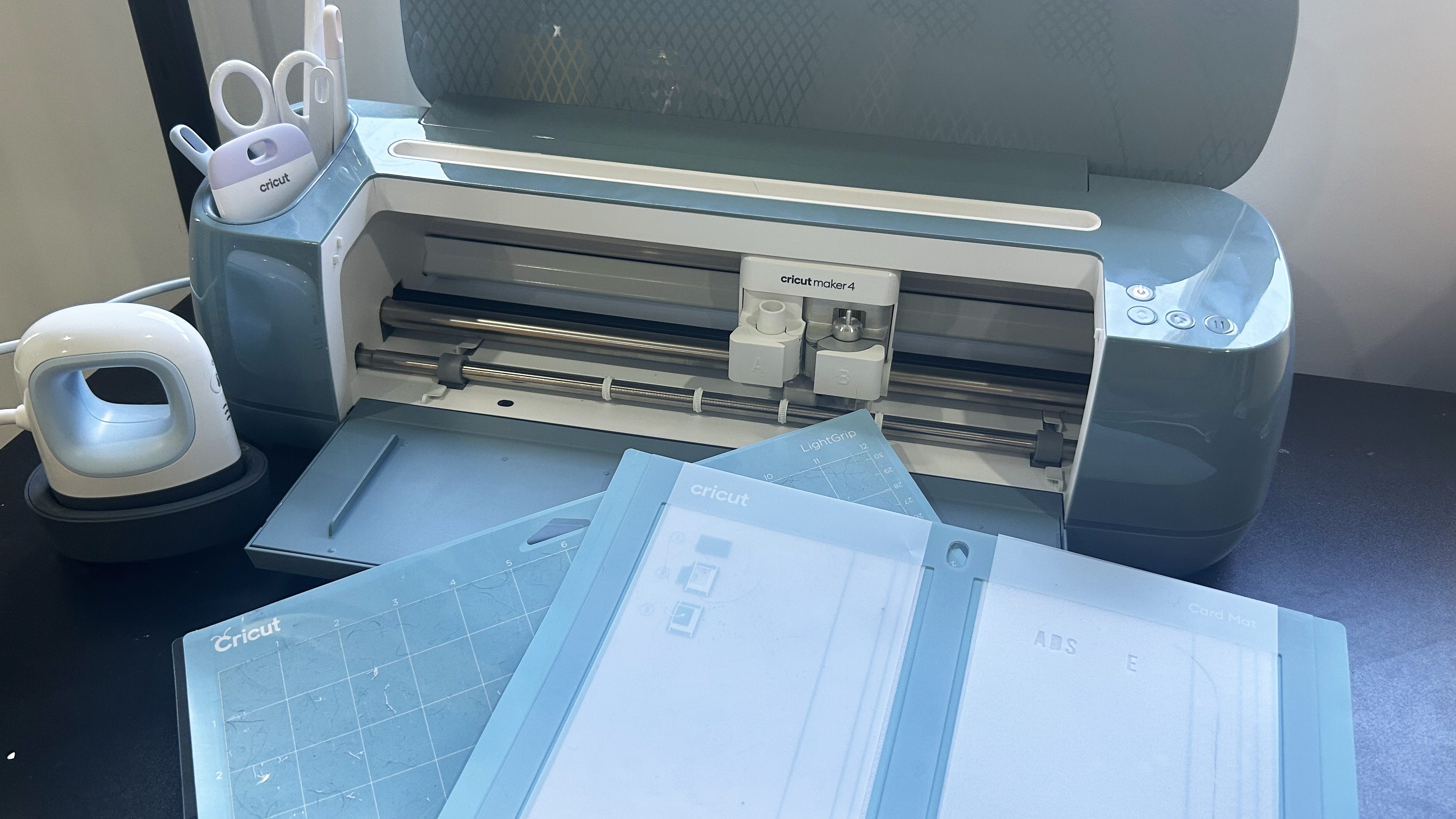 Cricut Maker 4 with tools, mat and card mat and the Cricut Mini heat press on the left (not included with Cricut Maker 4)