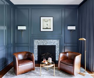 room with blue walls and fireplace with two leather club chairs