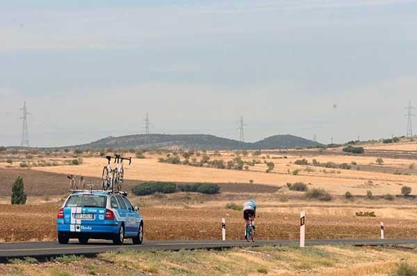 A Milram rider rolls off into the distance, with his team car in tow.