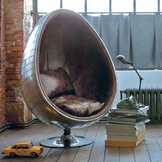 Egg chair from Maisons du Monde in a loft style apartment with wood flooring and books as a coffee table
