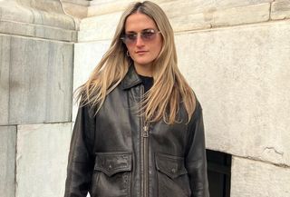 Editor Eliza Huber wears brown leather jacket with 90s-style sunglasses.