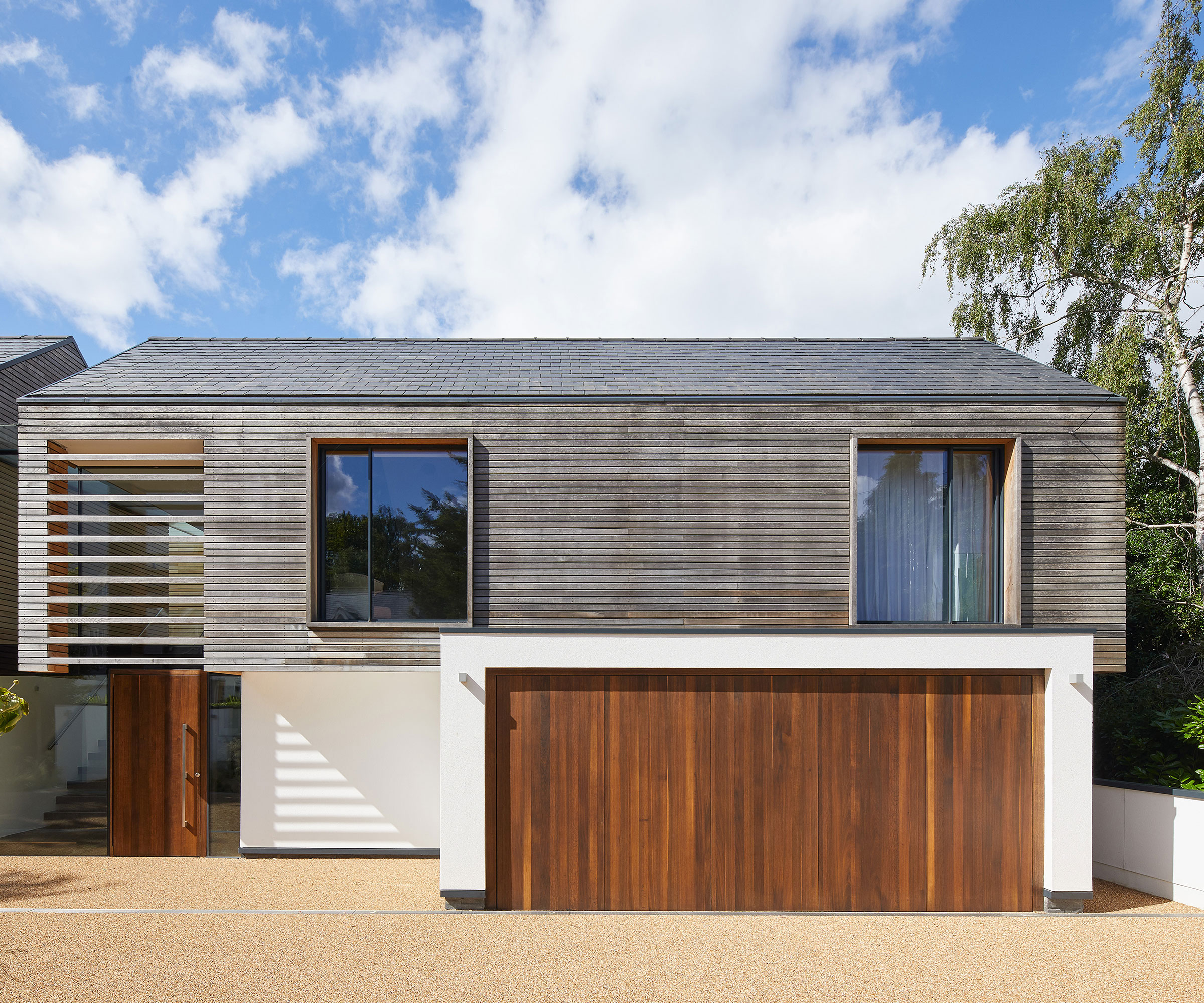 modern house with horizontal timber cladding and fumed oak front door and garage door with resin driveway