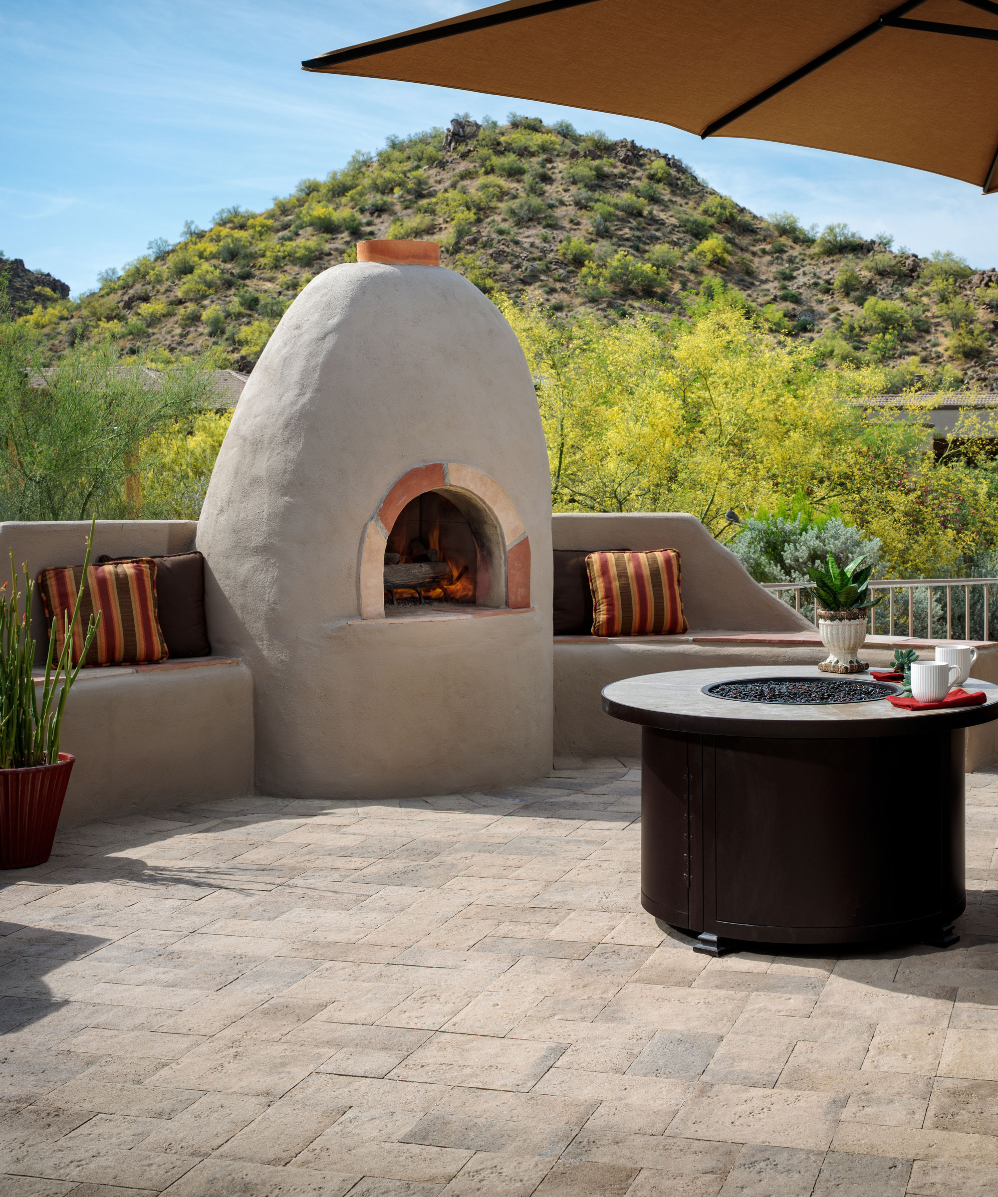 natural landscaping materials including tiles, built in seats with cushions and outdoor fireplace, plus table and plants