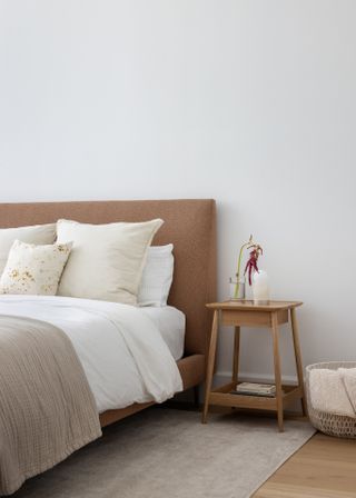 A bedroom with pillows and a blanket with a stylish wooden bedside table