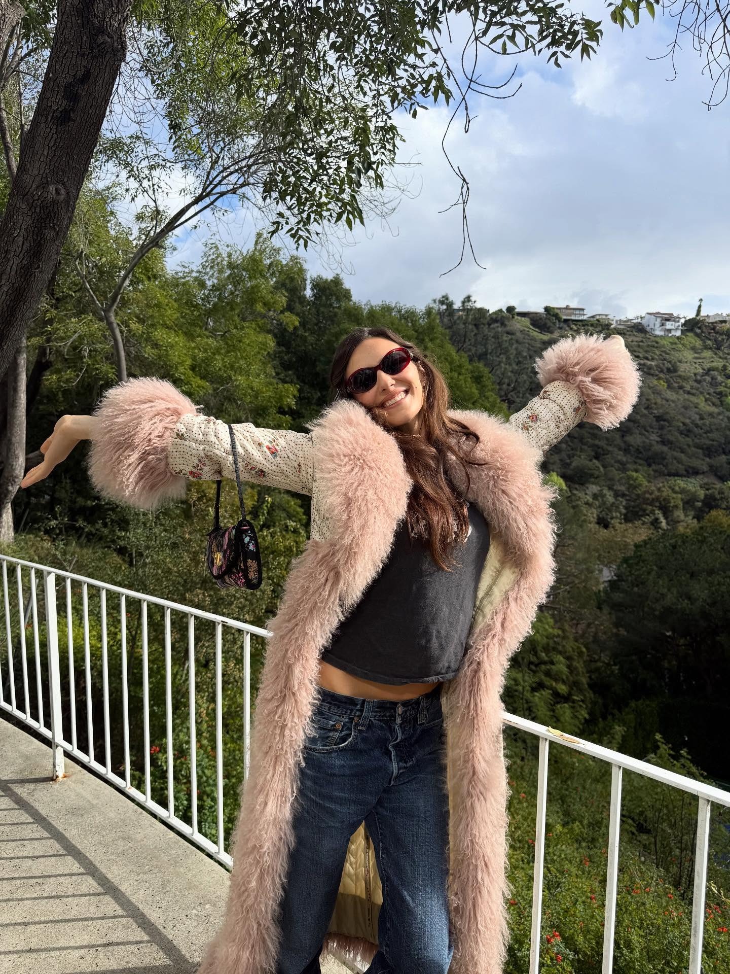 Devon Lee Carlson wearing a pink fur trim coat with a T-shirt and jeans.