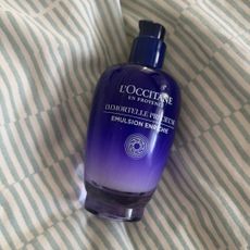 LOCCITANE IMMORTELLE NIGHT CREAM BOTTLE LYING ON A BED