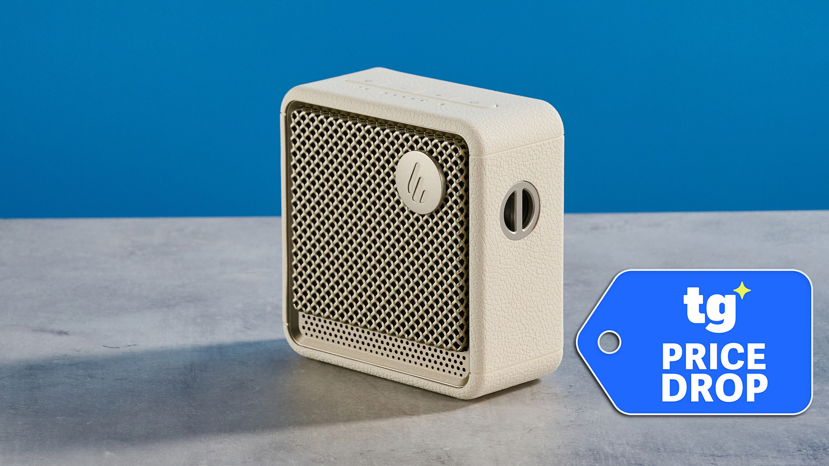 Edifier ES20 Bluetooth speaker in ivory photographed on a gray table in front of a blue background. 