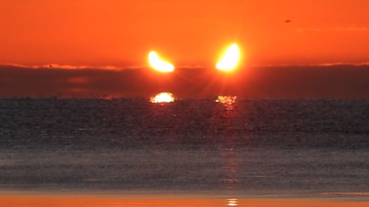 partial solar eclipse during sunrise, the sun looks like a pair of horns rising above the horizon.