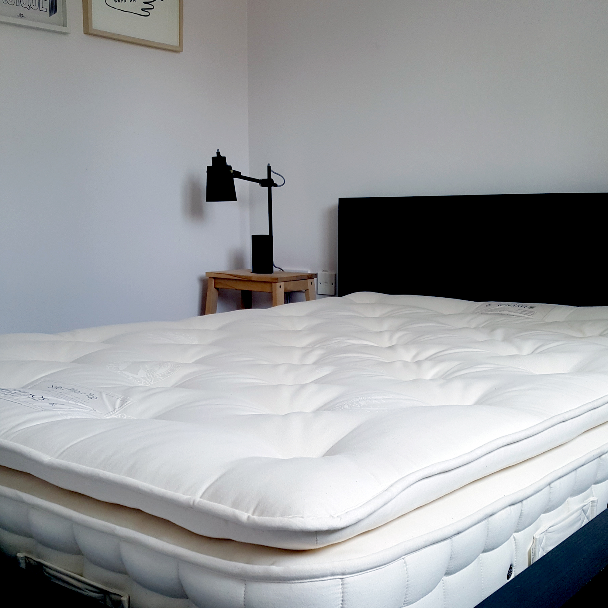 The Hypnos Pillow Top Classic mattress being tested in a bedroom with pale pink walls and a black bed