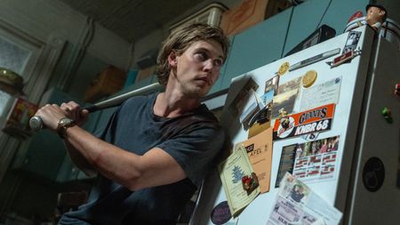 Hank (Austin Butler) readies a baseball bat in his kitchen inside his apartment in a scene from "Caught Stealing"