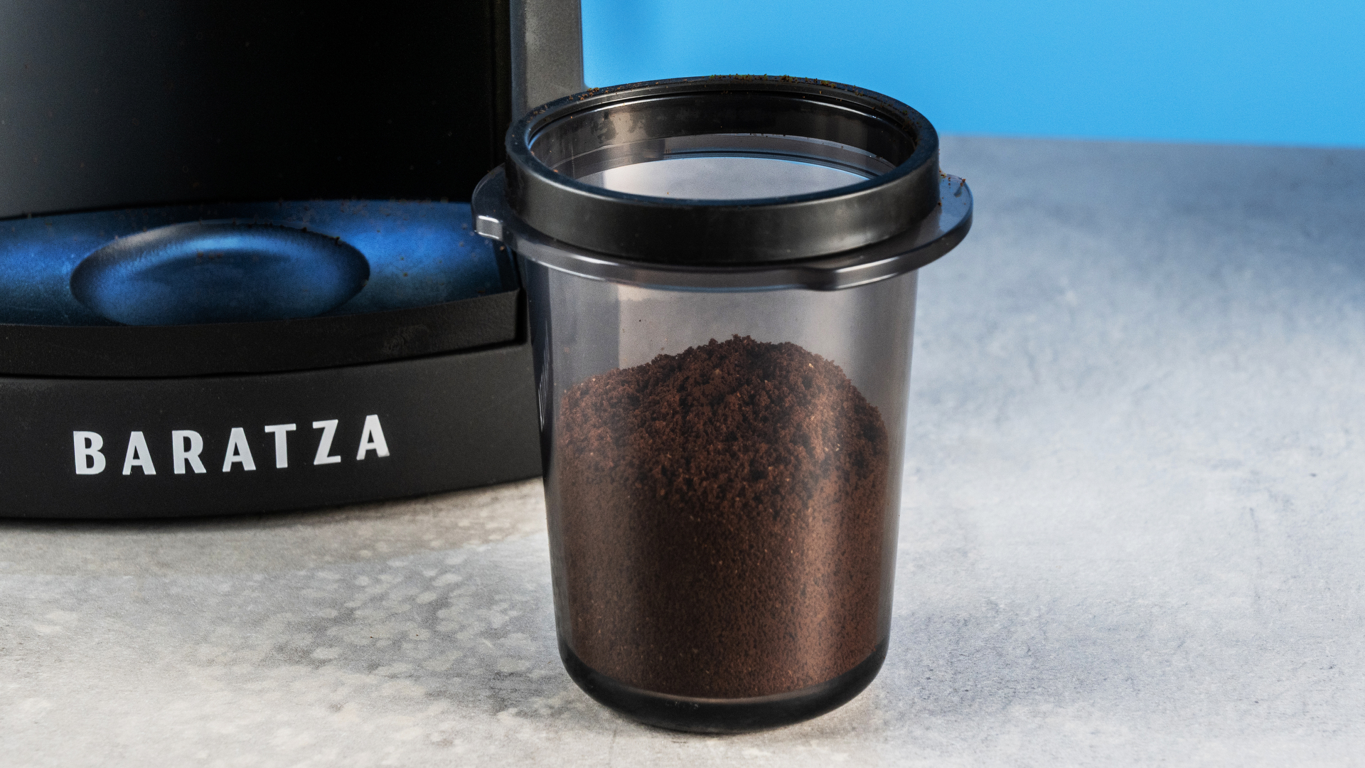 the baratza encore esp pro coffee grinder photographed against a blue tom's guide background with a bag of coffee to the side and showing the grinder in action