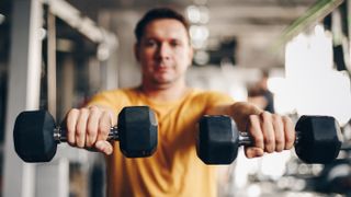 Man performs front raise with dumbbells