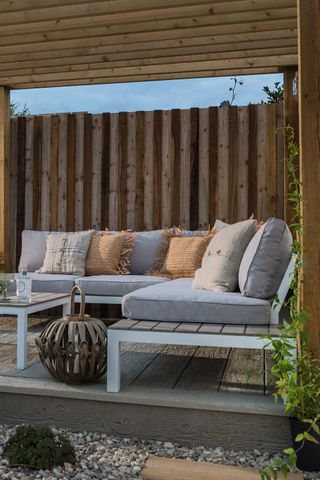 raised garden decking with grey outdoor sofa and rustic throw pillows
