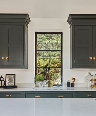 A green and white kitchen with antique brass hardware