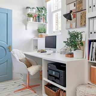 Home office with white desk, upholstered desk chair, laptop and printer