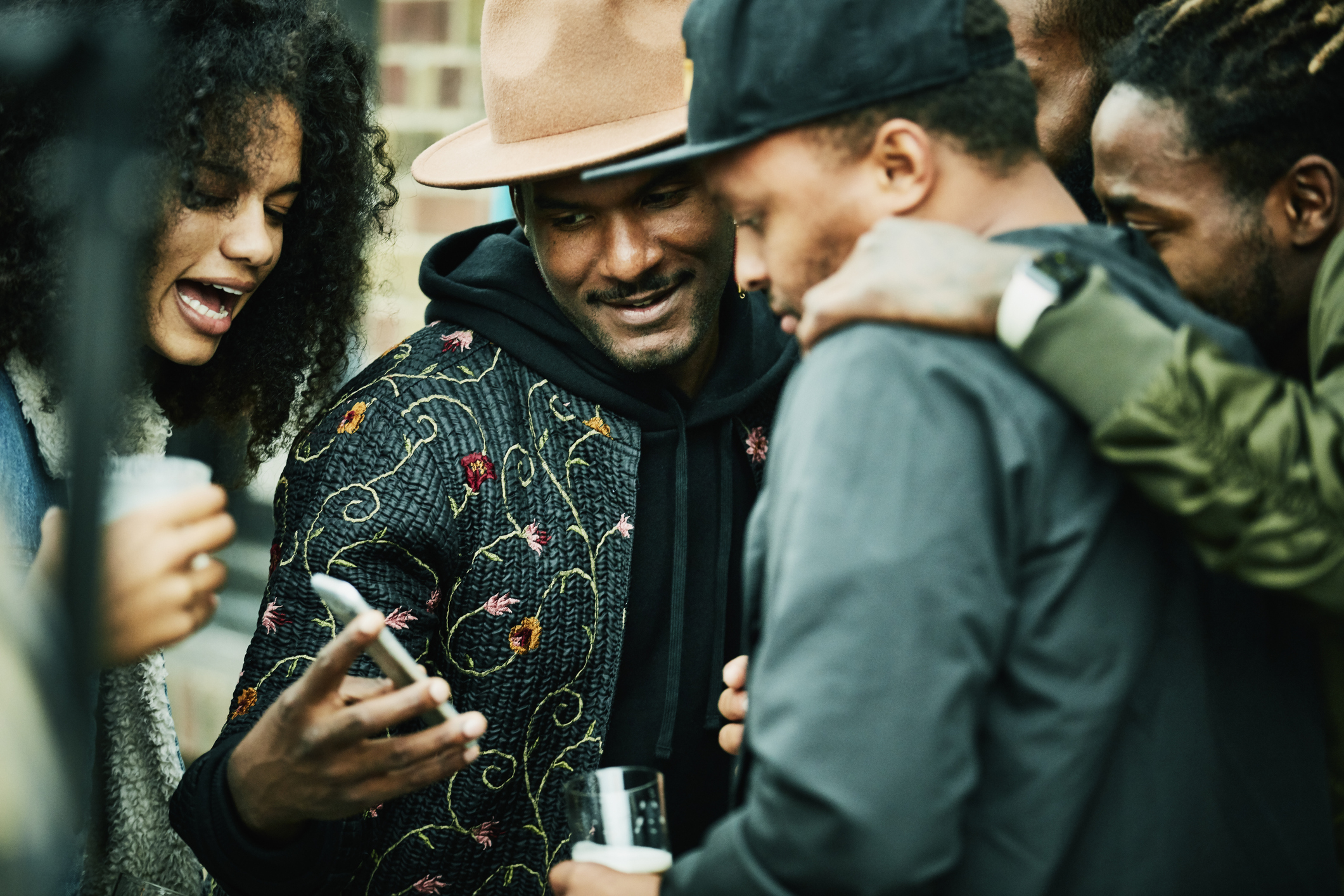 Friends looking at smart phone during party at outdoor restaurant