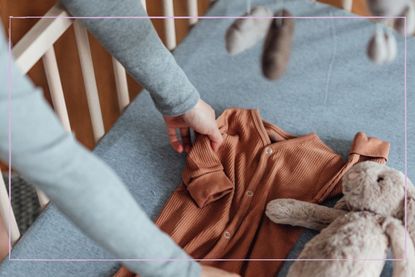 mother placing baby grow and soft toy bunny inside empty cot