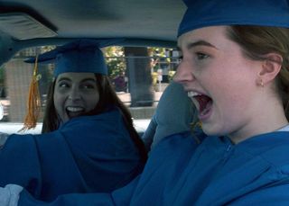 beanie feldstein and kaitlyn dever screaming in a car wearing cap and gowns in booksmart