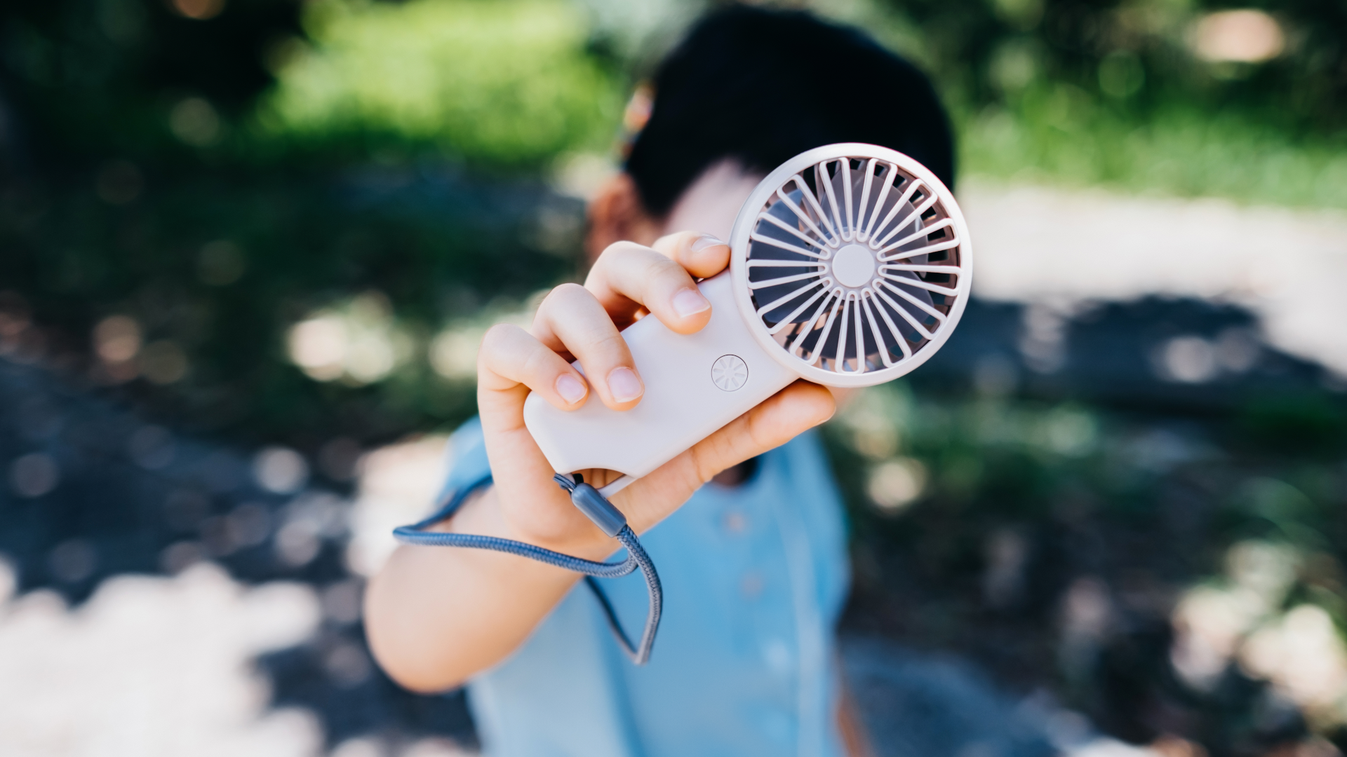 A boy holding a portable fan