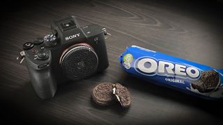 A photo of the 'Oreo' camera lens on a Sony A7 IV next to a packet of Oreo's