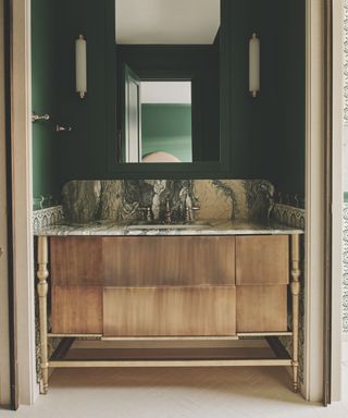 Green painted bathroom with wooden and marble topped sink unit