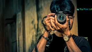 A man takes a photo with a Nikon camera