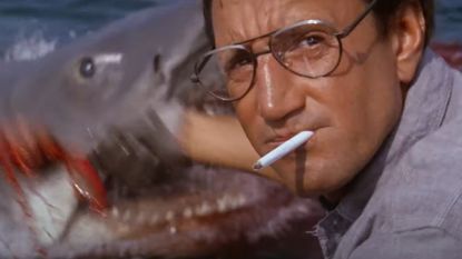 Roy Scheider as Chief Martin Brody sitting in front of a shark during the horror movie Jaws. 