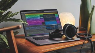 An Apple MacBook Pro on a table with Logic Pro running and a pair of studio headphones