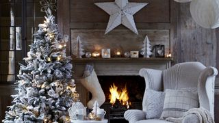 a white snowy christmas tree in a living room in front of the fire