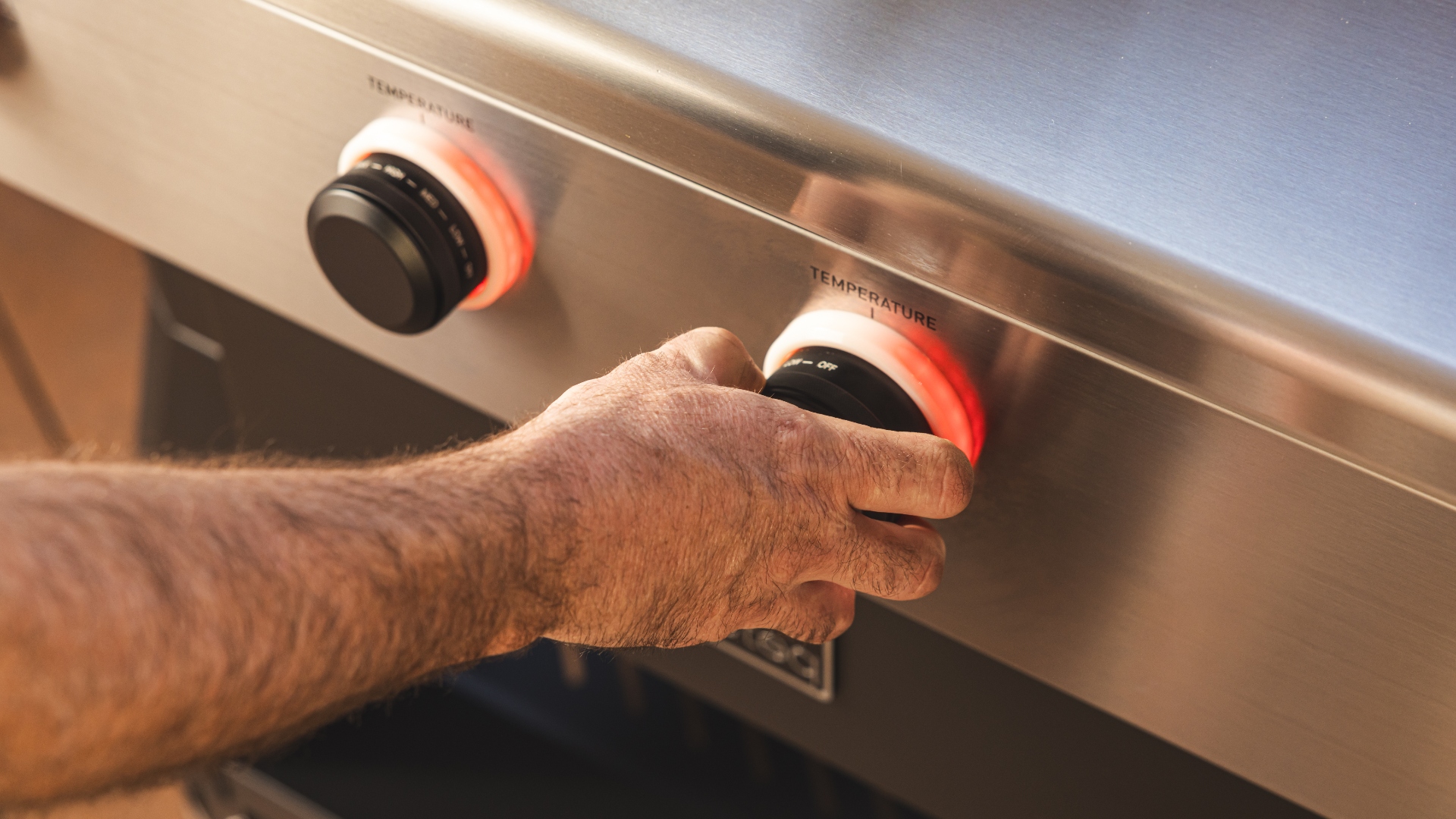 A man turning up the temperature dial on the Recteq X-Fire Pro