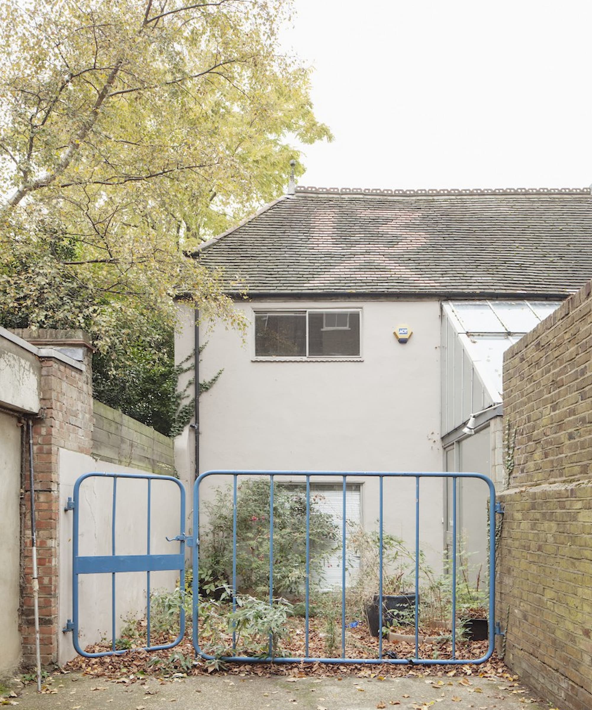 A rundown house with a temporary fence in a driveway