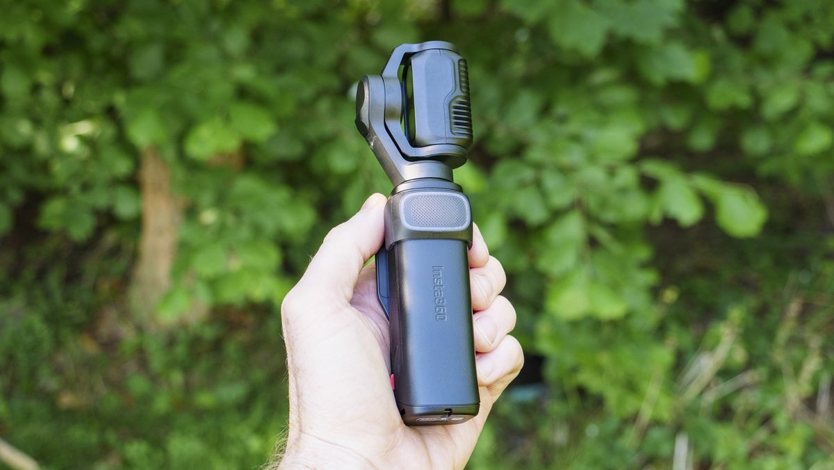 Insta360 Luna Ultra vlogging camera in person's hand, turned off, leafy background