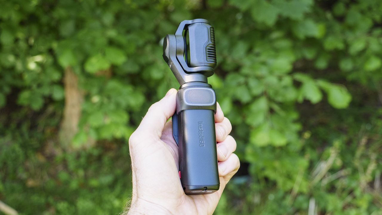 Insta360 Luna Ultra vlogging camera in person's hand, turned off, leafy background