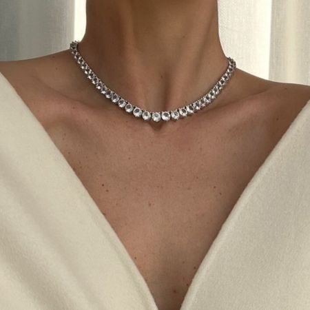 a woman wearing a white blazer and diamond choker