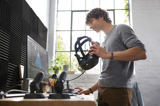 Young man with VR headset standing in front of a computer monitor