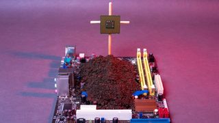 A dead motherboard with soil on it and a crucified CPU