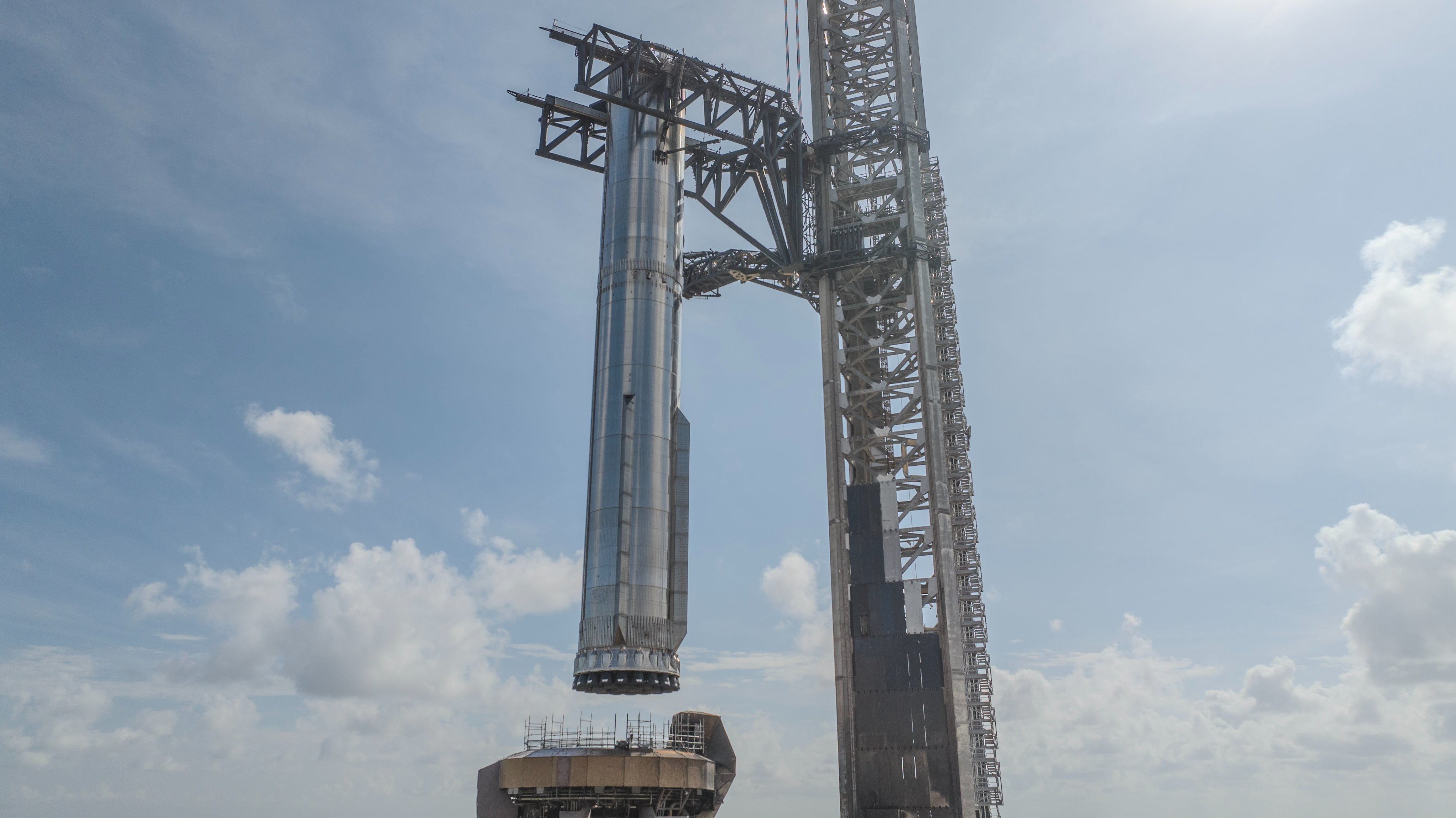 a giant metal launch tower lifts a silver rocket using two metallic arms